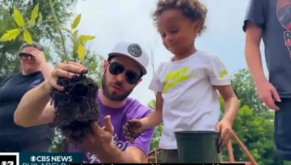 Erik Schroeder, a board member with Grands Stepping Up, gets ready to add a plant to the community garden as a young child looks on.