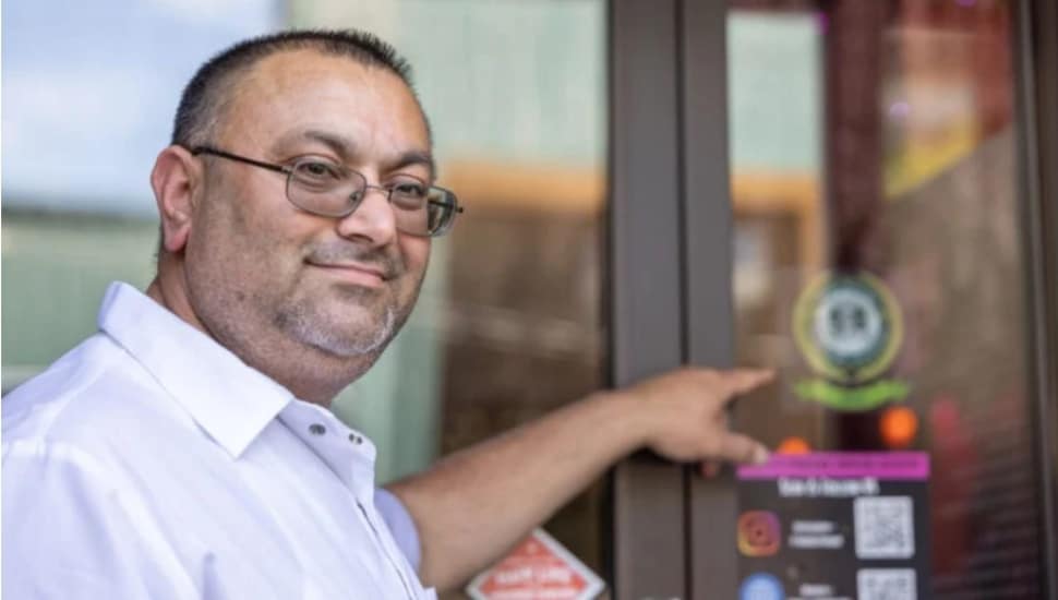 Pushpinder Singh, owner of Shere-E-Punjab Indian Cuisine in Media, Pa., points to the Media Sustainable Storefronts on the door of his restaurant.