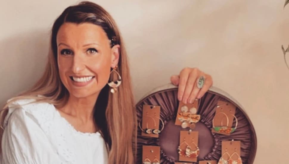 Courtney Jacob holds an open display case of her jewelry.