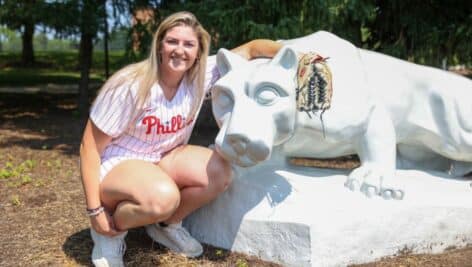 Penn State Brandywine alumna Farrell Everett poses with the Nittany Lion statue on the Penn State Brandywine campus.