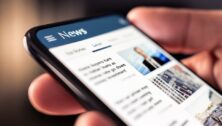 Man holding a cell phone showing current headlines