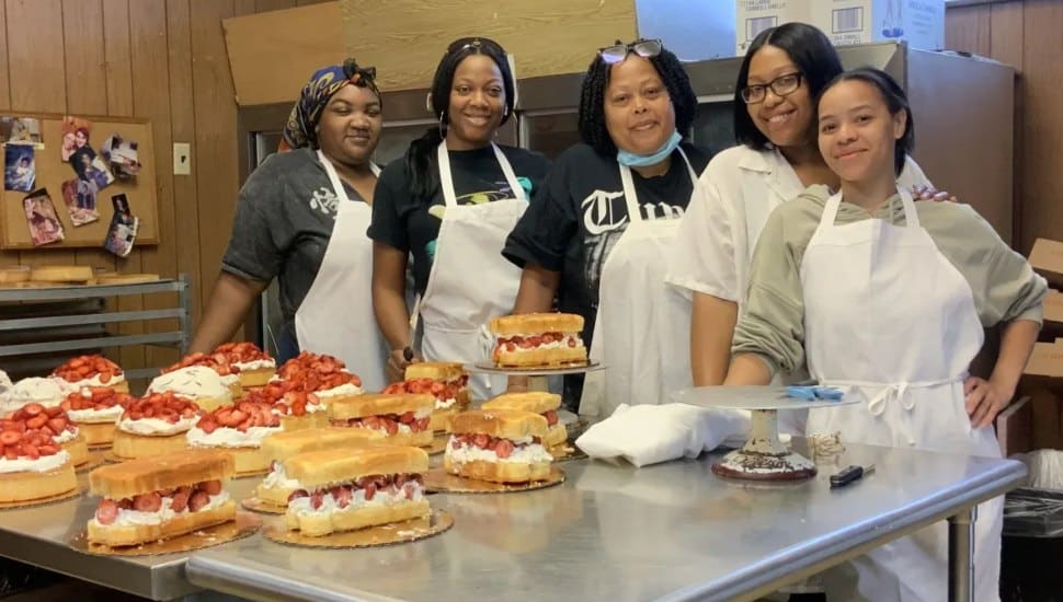 Employees at the Chester Kyj's Chester store gather around the decoration table for the strawberry shortcake.