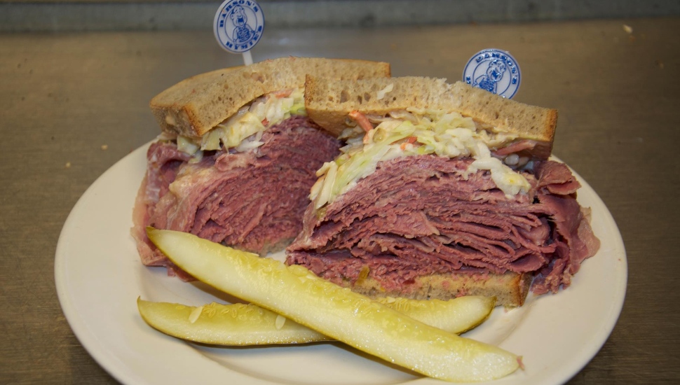 A giant corn beef special sandwich with two pickles.