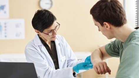 A woman doctor examines a rash on a male patient.