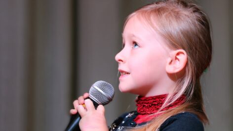 A little girl spells out a word at a spelling bee competition.