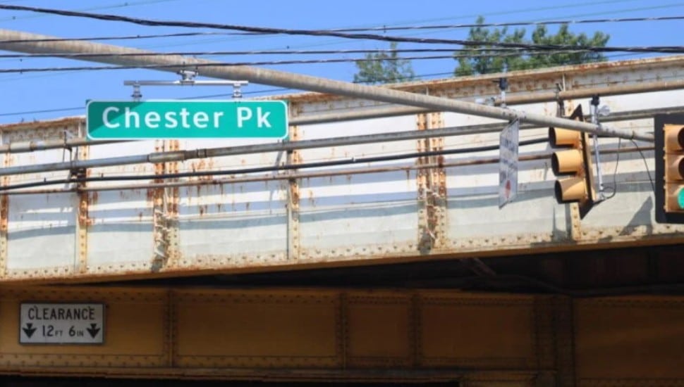 A Chester Pike road sign on a rusty-looking bridge.