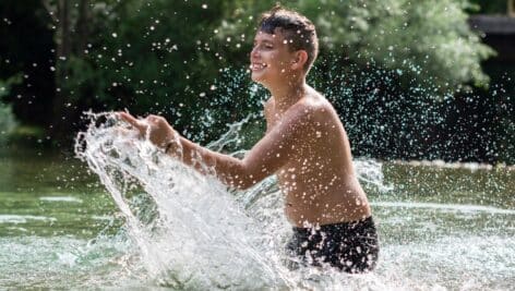 Smiling teenage boy playing in a creek