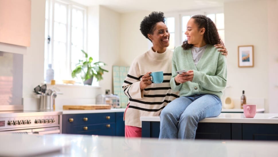 A mother and daughter are having a pleasant conversation in the kitchen.