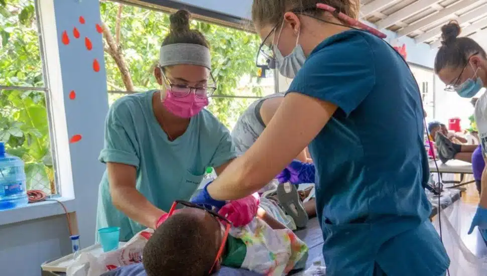 Pennsylvania College of Technology dental hygiene student Rachel A. Doyle (left) works alongside Regan G. Kline, an associate degree graduate and current student in the college’s bachelor’s in dental hygiene, to provide dental care to a child at a community center in the Dominican Republic village of Zion.