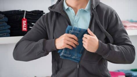 A man slips a pair of jeans into his jacket.