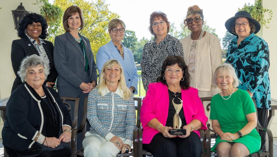 2024 Athena Award winner Peg DeGrassa (seated, bottom row, third from left) holds her award surrounded by friends and supporters at the Delaware County Chamber of Commerce 2024 Athena Award luncheon Oct. 9.