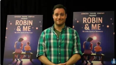 Delaware County actor Dave Droxler stands next to posters promoting his one-man show, "Robin & Me."