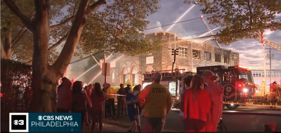 Firefighters work to contain the Oct. 7 fire at St. Francis of Assisi School in Springfield as onlookers watch.
