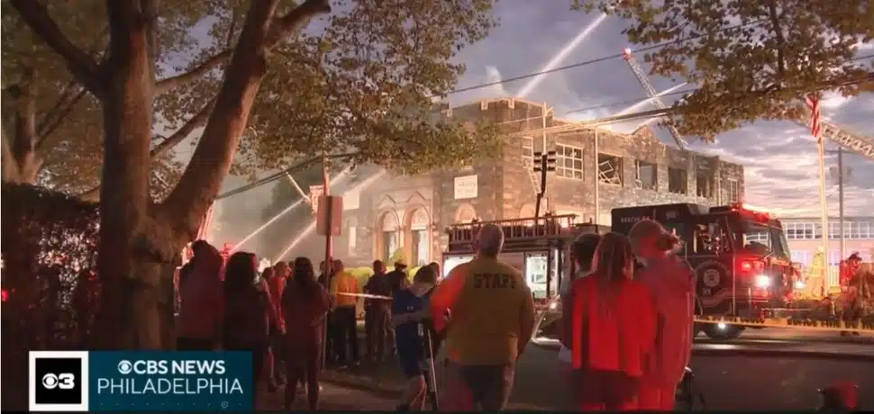 Firefighters work to contain the Oct. 7 fire at St. Francis of Assisi School in Springfield as onlookers watch.