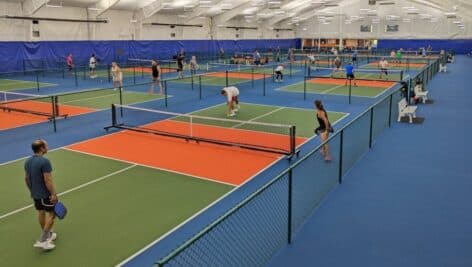 Players play pickleball at an indoor pickleball center.