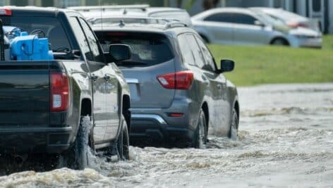 Cars travel through flooded streets.