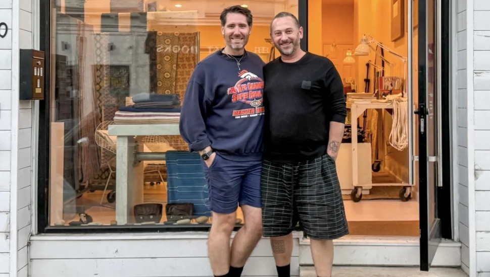 Two men, including Matthew Addonizio, owner of Approved Textiles, stand in front of the fabric shop.