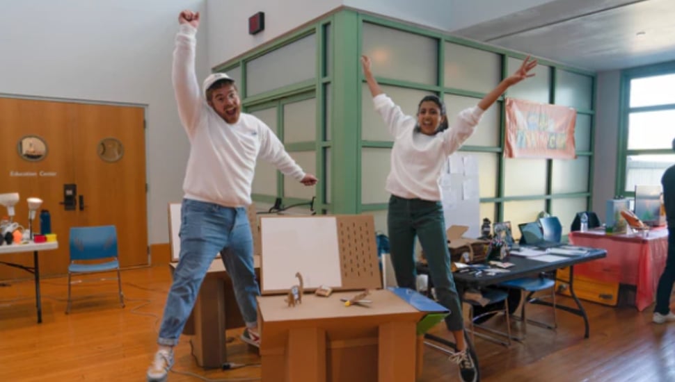 The founders of ChompShop, Kausi Raman and Max Liechty excitedly jump into the air.