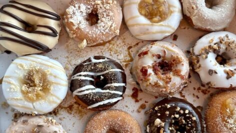 A table top covered with different kinds of doughnuts.