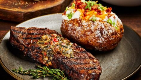 Steak and a baked potato available at Firebirds Woodfired Grill.