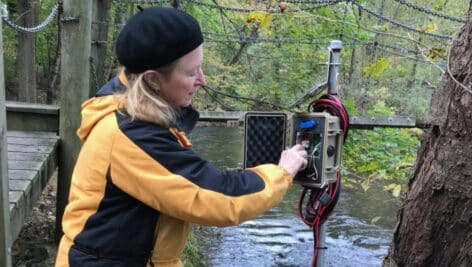 Stroud Water Research Center volunteer Carol Armstrong performs maintenance on a stream monitoring station.