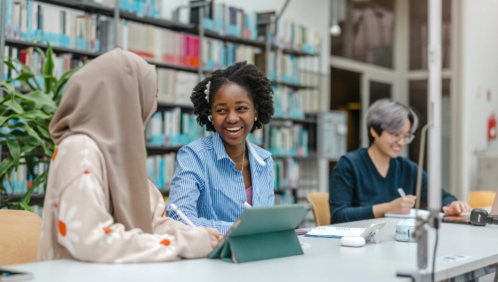 Multiethnic group of students sitting in a library and studying together.