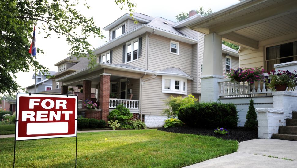 A home with a for rent sign in a pleasant suburban community.