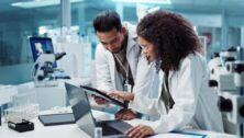 Two researchers in white coats work in a laboratory.