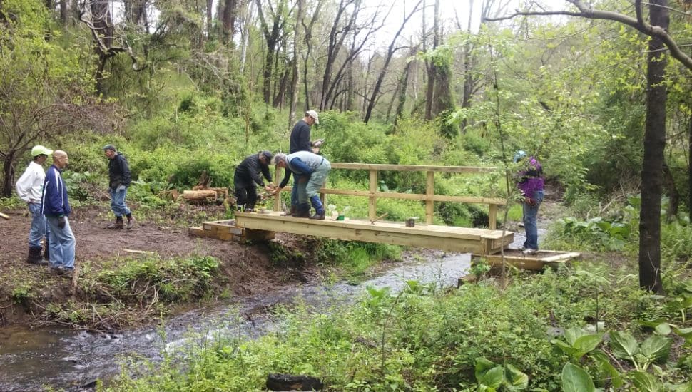 Volunteers from the Friends of Ridley Creek State Park work on a trail bridge at the park.