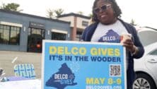 An enthusiastic volunteer holds a Delco Gives sign promoting the charitable giving day.