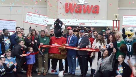 Wawa store general manager Lauryn Hughes cuts the ribbon on the latest Wawa in Ridley Township as a crowd gathers around.