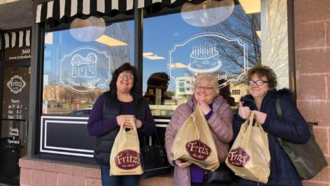 Three happy women customers holding Fritz Bakery bags outside the bakery.