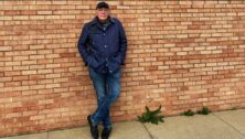 Author James Patterson leans against a wall.