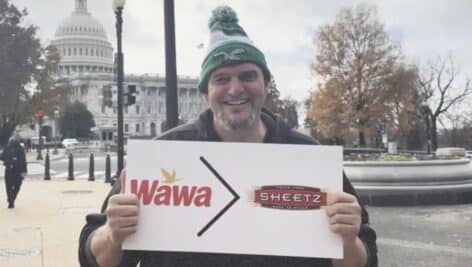 U.S. Sen. John Fetterman stands outside the U.S. Capitol holding a sign indicating that Wawa is greater than Sheetz.