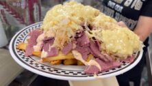 A plate of corn beef and sauerkraut over French fries.