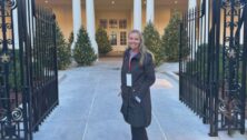 Nicole Radio of West Chester, a White House Christmas decoration volunteer, stands at the gates to the White House entrance.