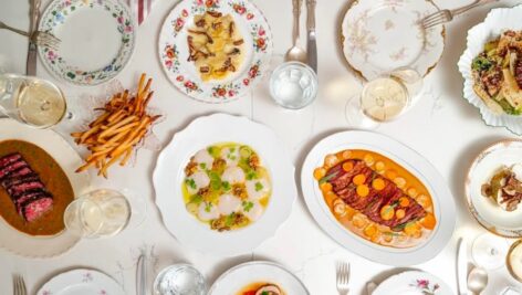 A variety of entrees from various restaurants sit on a table with a white tablecloth.