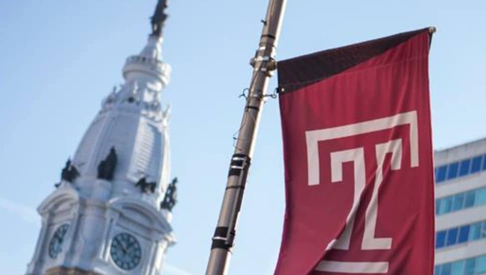 The Temple University flag with Philadelphia City Hall in the background.