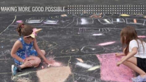 Children do chalk art on an asphalt lot.