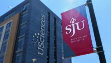 A St. Joseph's University flag flies next to a University of the Sciences campus building.