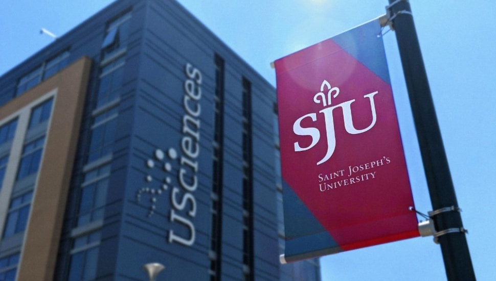 A St. Joseph's University flag flies next to a University of the Sciences campus building.