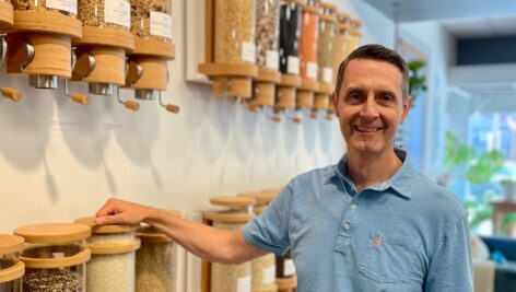 A man stands next to bulk items for sale at The Yardley Refillery.