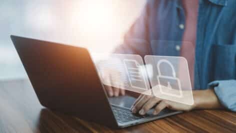 A person at a laptop computer trying to break into a locked file.