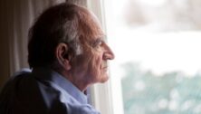 An older gentleman looks out the window in contemplation.