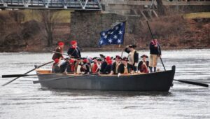 A boat on the Delaware River full of Colonial re-enactors performing Washington crossing the Delaware.