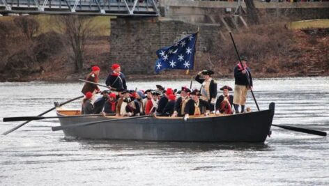 A boat on the Delaware River full of Colonial re-enactors performing Washington crossing the Delaware.