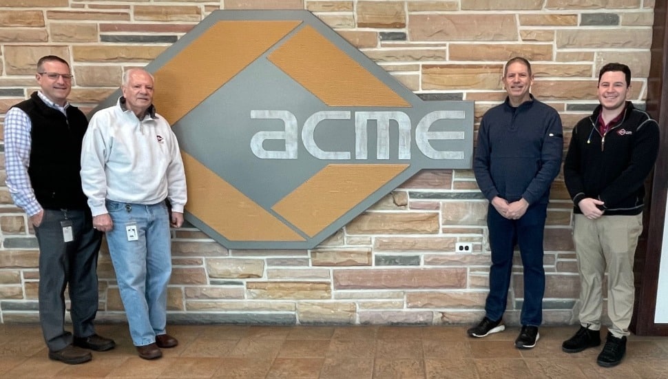 Family-owned business leaders pose for a picture in front of company signage.