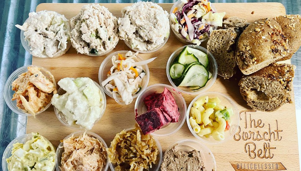 A table filled with Borscht Belt Deli sandwiches and salads.