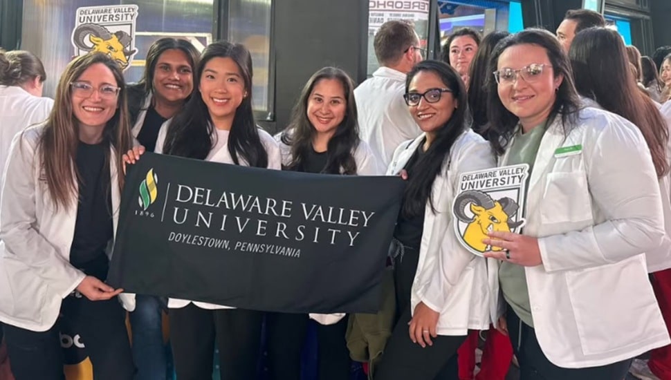 College students pose for a group photo with a banner.