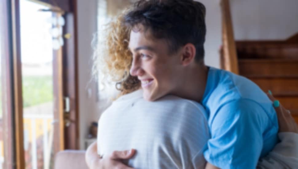 A young man hugs a woman.